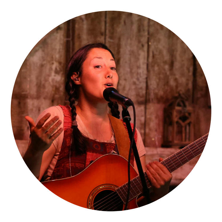 femme qui chante au micro avec guitare en main