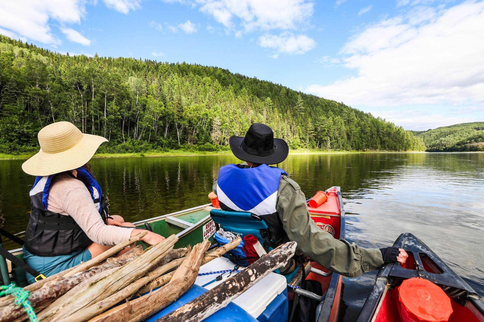 deux personnes dans des embarcations canoes, qui regardent à l'horizon sur la rivière