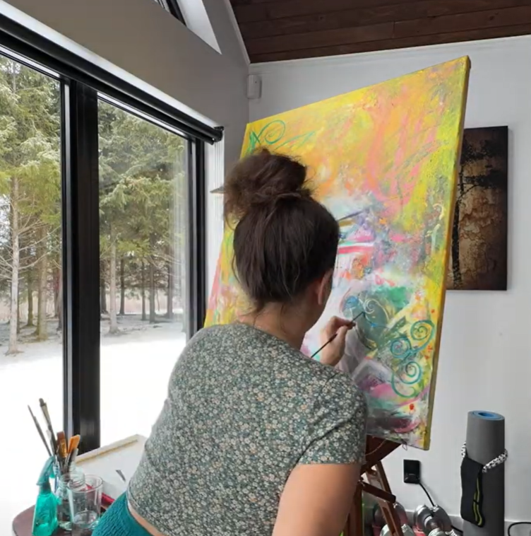 femme qui peint sur une toile avec de la peinture colorée