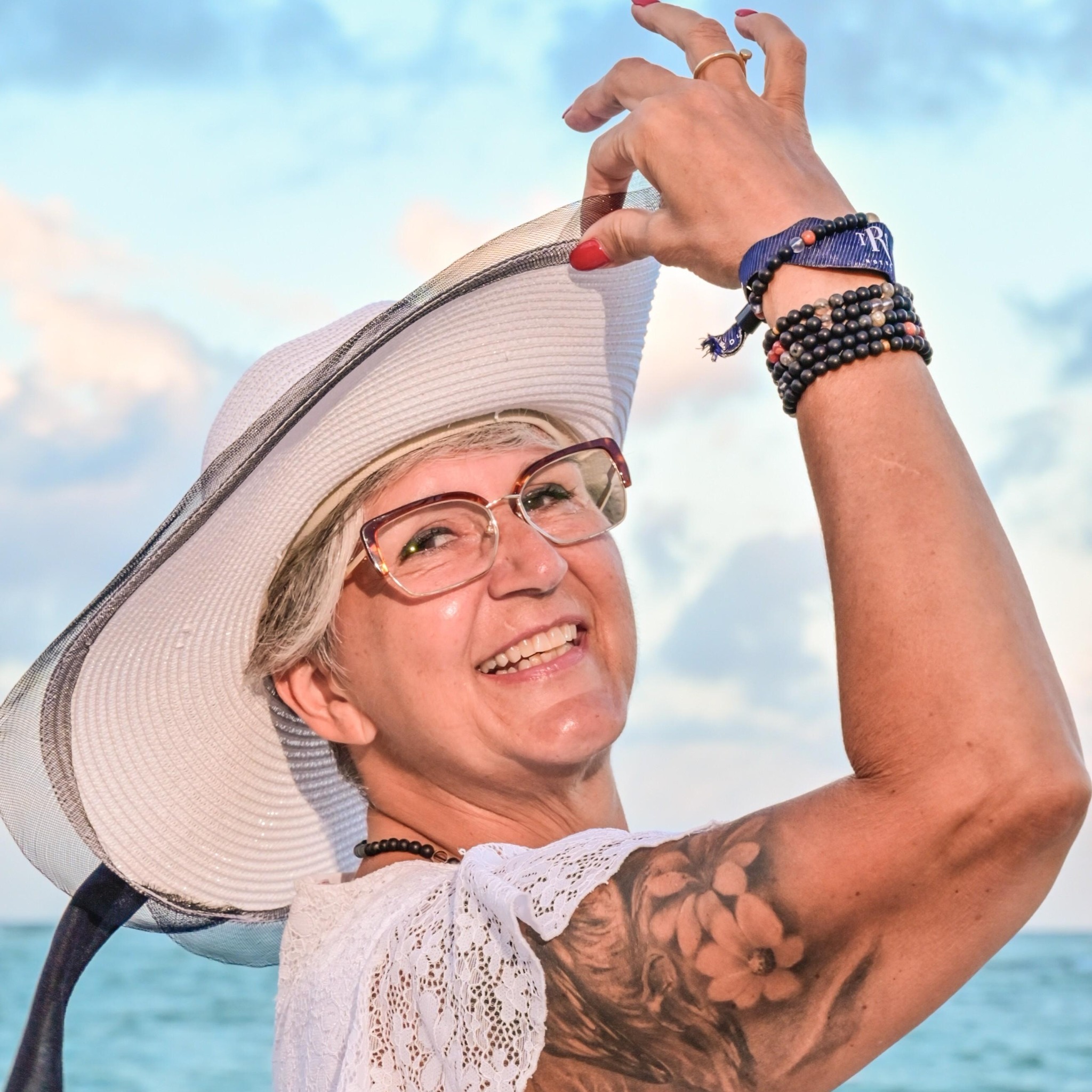 femme souriante, chapeau soleil sur fond de nuages bleus